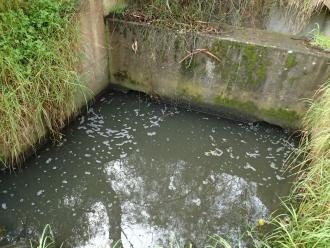 Grey sudsy water in pit retention area.