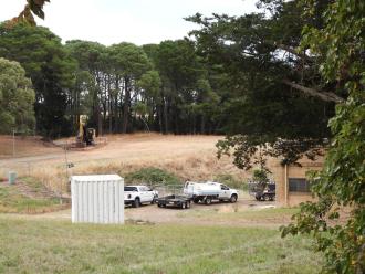 Heavy earthmoving equipment in the background with earth channel and cordon around it.
