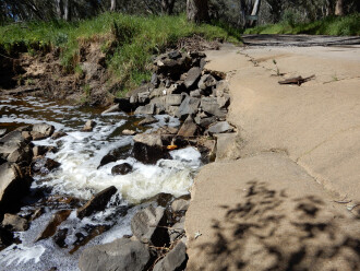 taken on 7/10/2026 showing water flowing through the under-road pipe